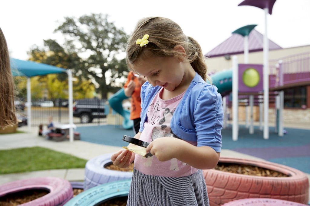 Child on Playground looking through Magnifying Glass
